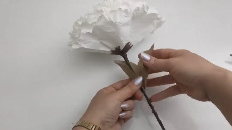 DIY yapraklarını kendi başına yap kağıt havlu çiçeğine yapıştıran kişi