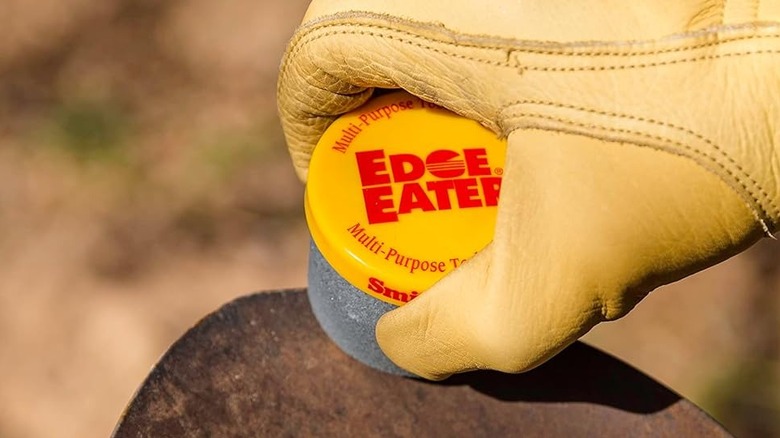 Amazon'dan Smith's Edge Eater ile metal bir aleti keskinleştiren sarı deri eldivenli bir elin yakından görünümü