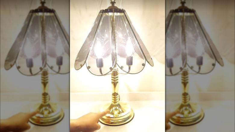 Açık tenli bir el, 80'lerin vintage dokunmatik lambasını yakıyor.