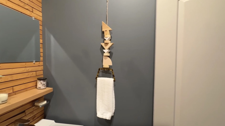Geometrik ahşap bloklardan yapılmış bir DIY el havlusu askısı ve bir el çantası sapı banyoda asılı duruyor.