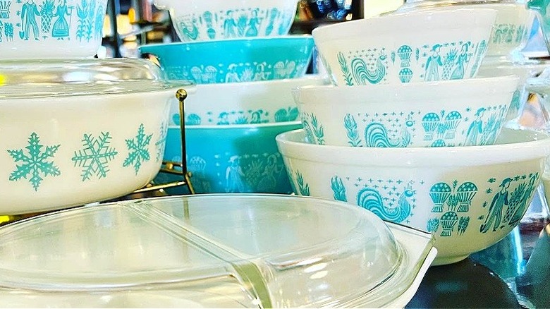 Vintage bir mağazada bir masanın üzerine yığılmış çeşitli boyutlarda Amish Butterprint Pyrex kaselerin koleksiyonu