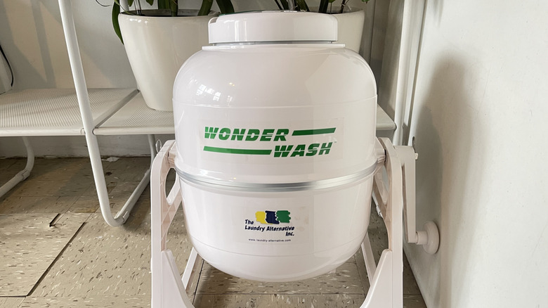 Beyaz taşınabilir WonderWash çamaşır makinesi yerde oturuyor