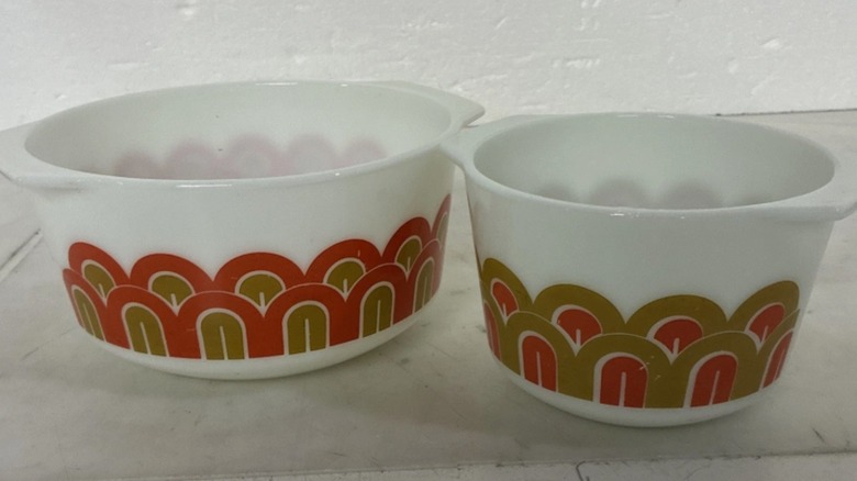 Altın ve turuncu kemerlerle süslenmiş iki adet düz kenarlı beyaz Pyrex kase