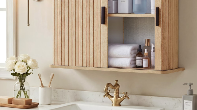 Modern bir evde lavabolu makyaj masasının üzerinde yivli ahşap sürgülü kapılara sahip bir banyo dolabı.