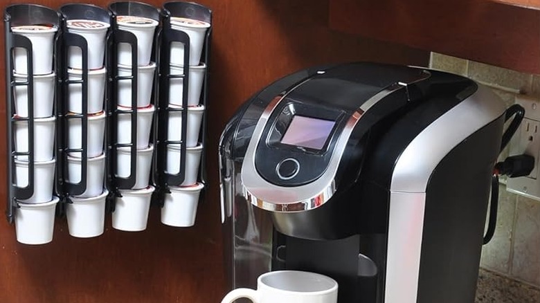Keurig kahve makinesinin yanındaki duvarda asılı olan Storagenie K Bardak Tutucu