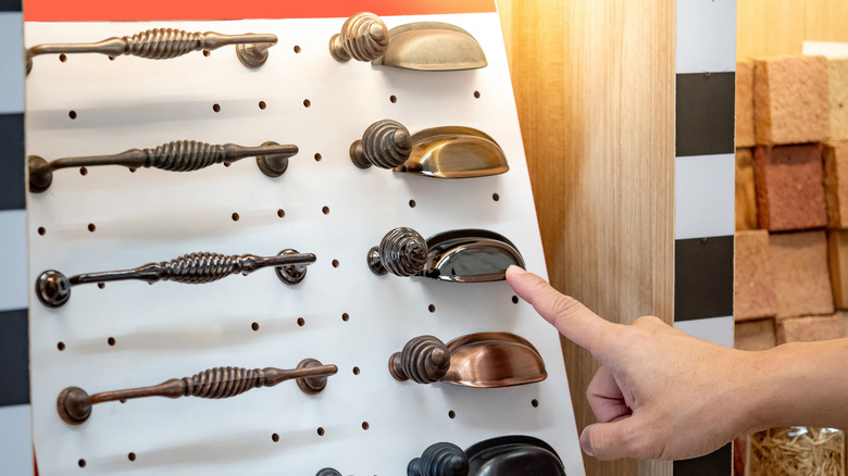Bir ev yenileme mağazasında metal dolabı işaret eden bir el sergileniyor.