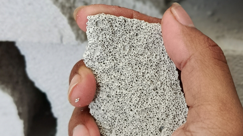 Elinde bir parça hücresel beton tutan bir kişi