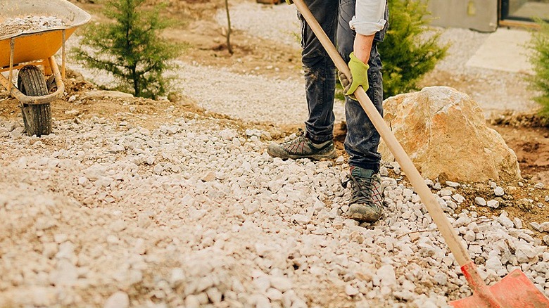 Bir kişi arka planda görülen malzemelerden oluşan bir el arabası ile DIY projesinin temelini hazırlıyor