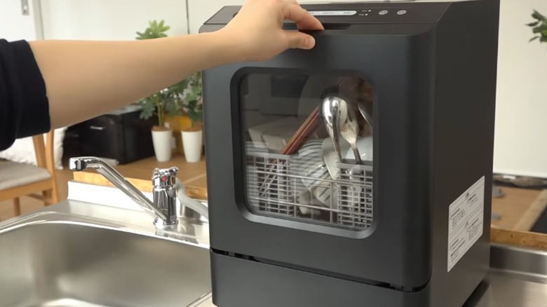 Tezgahta Thanko mini bulaşık makinesini açan kişi