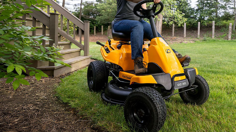 Cub Cadet CC30 H arkadan motorlu çim biçme makinesini kullanan bir kişi