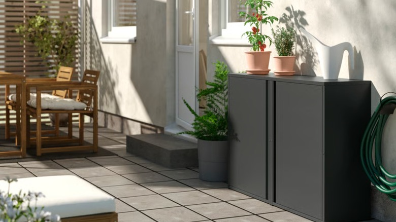 Üstte saksı bitkileri bulunan bir duvara dayalı IKEA dolaplı açık hava verandası
