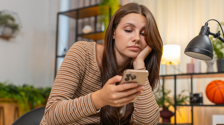 Kadın mutsuz bir şekilde telefonuna bakıyor
