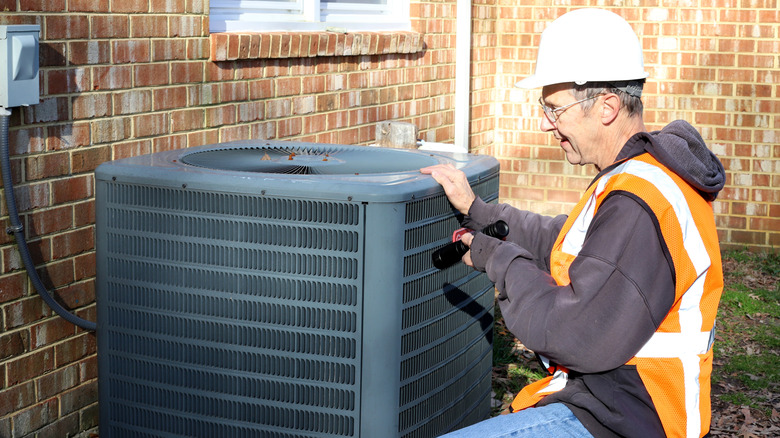 HVAC profesyoneli dış mekan AC kondansatörüne bakıyor