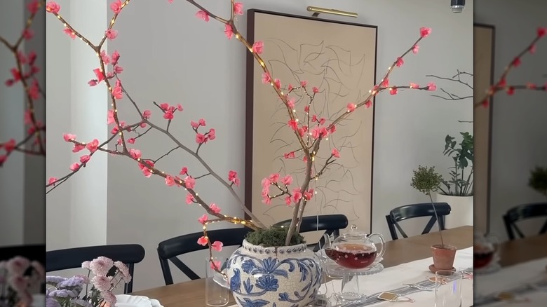Bir dalda pembe çiçekler tutan muhteşem bir vazo