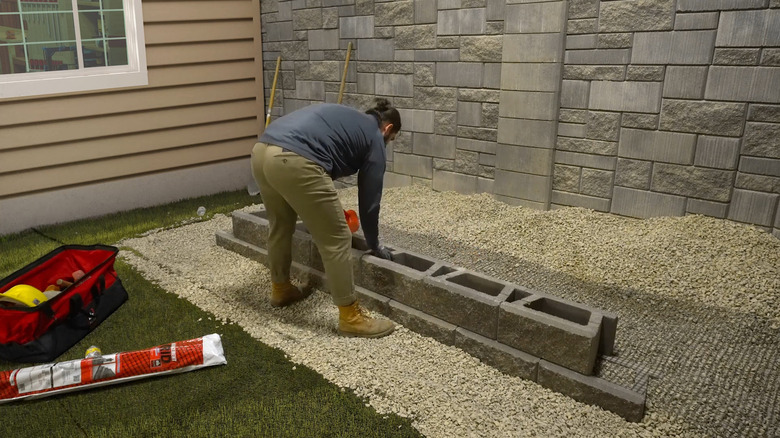 bir adam istinat duvarına geogrid yerleştiriyor