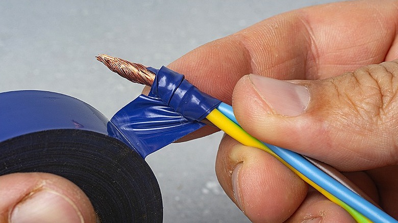 Elektrik telini elektrik bandıyla yalıtan bir kişinin yakın çekimi