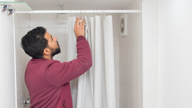 Bir girintiye gergili duş çubuğu takan bir adam