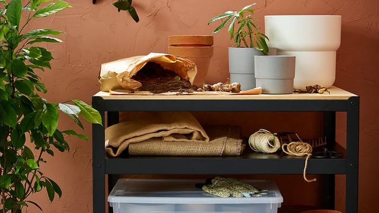 Bahçe malzemelerinin saklandığı açık renkli ahşap üst kısmı olan siyah metal IKEA BROR malzeme arabası