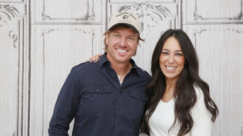 Joanna Gaines ve kocası Chip kollarını birbirlerine dolayarak gülümsüyorlar