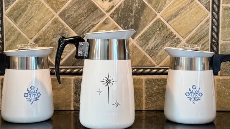 Corningware Yıldız Yağmuru ve Peygamber Çiçeği Mavisi süzgeçleri mutfak tezgahının üzerinde taş bir arka panelin önünde