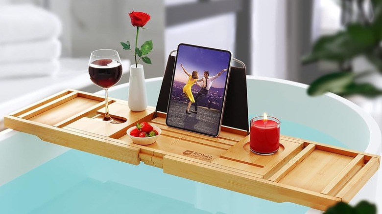 Küvetin karşısındaki Royal Craft Wood küvet tepsisinde bir kase çilek, bir gül, bir kadeh şarap ve üstünde yanan bir mum bulunur.