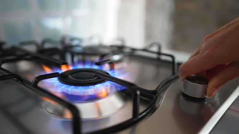 sobanın üzerindeki gaz ocağının düğmesini tutan kişi