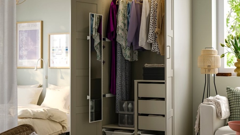 IKEA KOMPLEMENT Açılır Ayna, modern bir yatak odasında kıyafetlerle dolu bir dolabın içine yerleştirilmiştir.