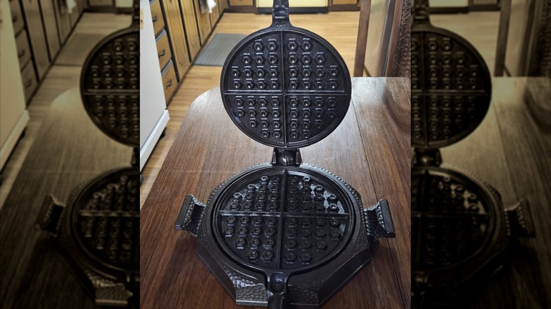 Açık ve ahşap bir masanın üzerinde duran Griswold dövülmüş waffle demiri örneği