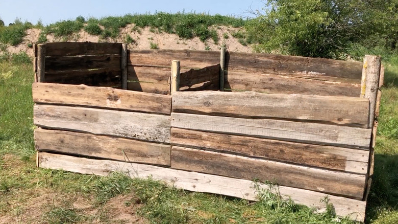 Geniş bir arka bahçede iki bölmeli, el yapımı ahşap kompost kutusu.