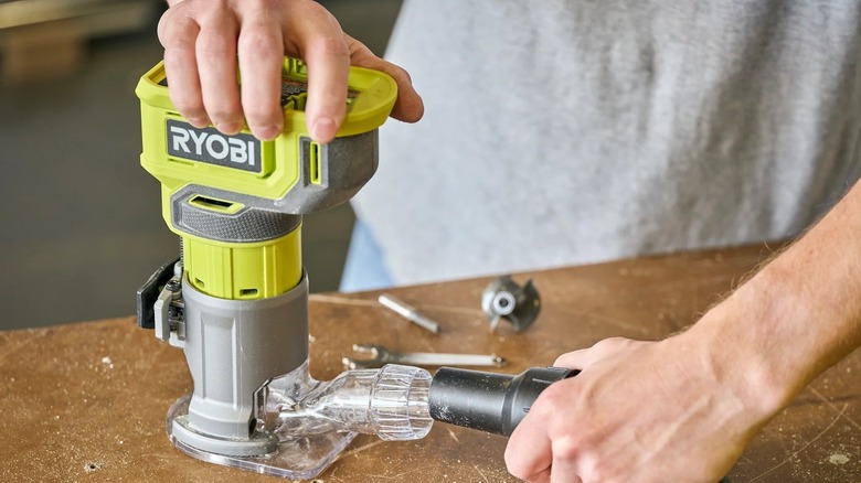 Elektrikli süpürgeye bağlı Ryobi yönlendirici kullanan kişi
