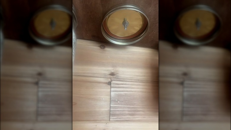 Dolabın tabanına takılı cam kavanoz kapağının yakından görünümü