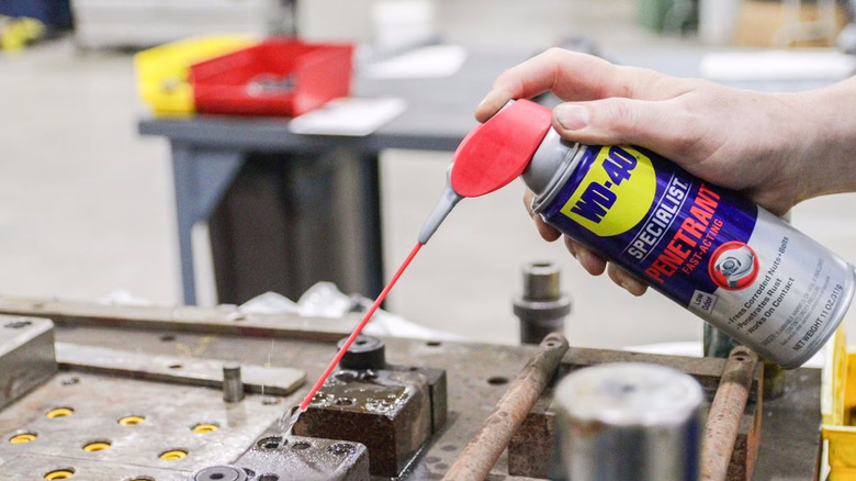 bir kişi cıvata tutucusuna WD-40 Specialist Penetrant püskürtüyor