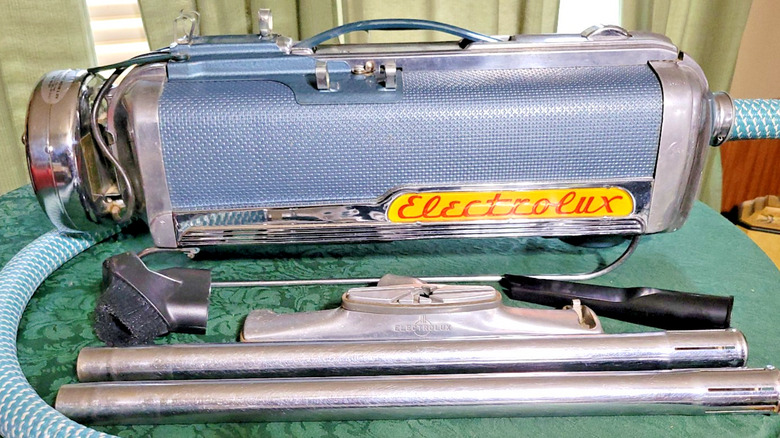 Aksesuarlarıyla birlikte vintage açık mavi ve krom kutulu elektrikli süpürge (Electrolux Model LX)