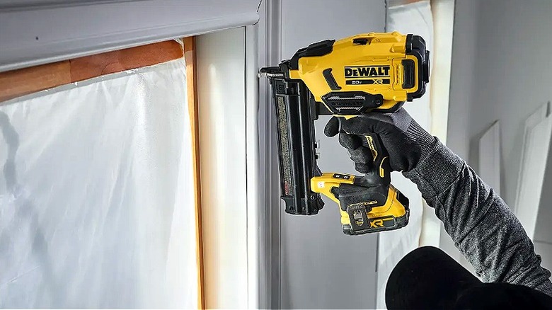 Pencere pervazını takmak için DeWalt çivi çakma tabancasını tutan elin yakın çekimi
