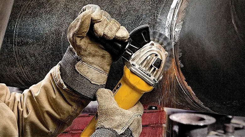 Büyük bir metal boruyu DeWalt taşlama makinesiyle kesen bir kişinin yakın çekimi