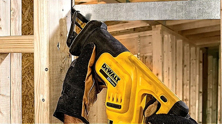 Metal ve ahşap arasındaki dar bir alanı kesmek için DeWalt panter testere kullanan bir kişinin yakından görünümü