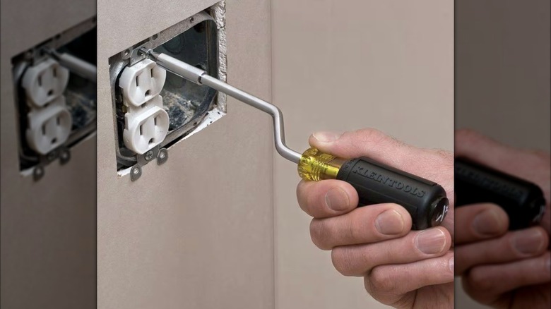 Elektrik prizinde Rapi-Driv tornavida kullanan kişi