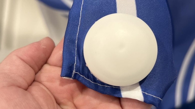 Üzerinde beyaz mıknatıs bulunan bir duş perdesi tutan kişi