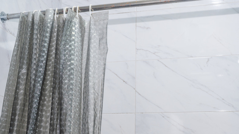 Plastik duş perdesi kaplamalı beyaz bir banyo.