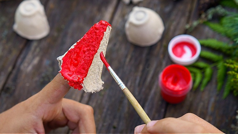 Yumurta kartonunun sivri kısmı kırmızıya boyanırken birinin parmağında duruyor