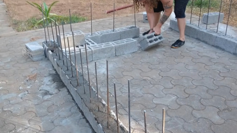 Yığılmış beton bloklardan duvar ören bir kişi