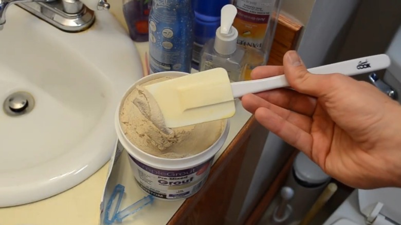 Harcı kauçuk spatulayla toplayan el
