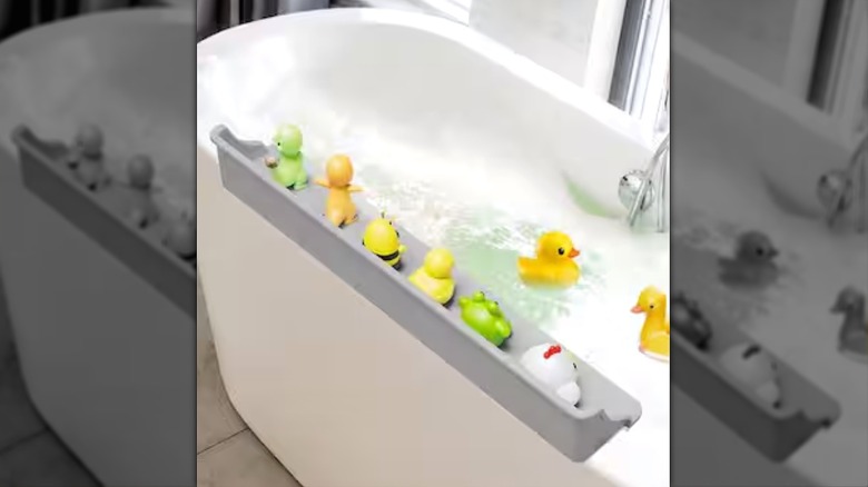 Beyaz bir küvetin üzerindeki Anqtovp sıçrama koruması ve üzerinde çocuk banyo oyuncakları duruyor.