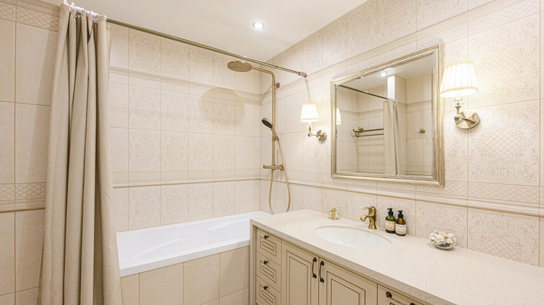 Bej duş perdeli bir küvet içeren güzel bir banyo iç mekanı.