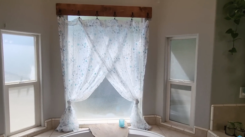 Perdeler banyodaki kancalarla ahşap bir kalastan sarkıyor.