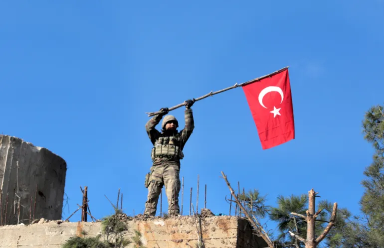 DOSYA -- 28 Ocak 2018 Pazar tarihli bu dosya fotoğrafında, Türk birlikleri, Kürtlerin elindeki Afrin bölgesini Suriye'nin Türkiye kontrolündeki Azaz kasabasından ayıran Bursayah tepesini korurken bir asker Türk bayrağı sallıyor. Planlanan ABD birliklerinin çekilmesi Suriye'nin kuzeyinde ve doğusunda bir boşluk açıyor ve Ortadoğu'daki tüm güçler arasındaki çatışma ve rekabet bu boşluğu doldurmaya yaklaşıyor. (AP Fotoğrafı, Dosya)