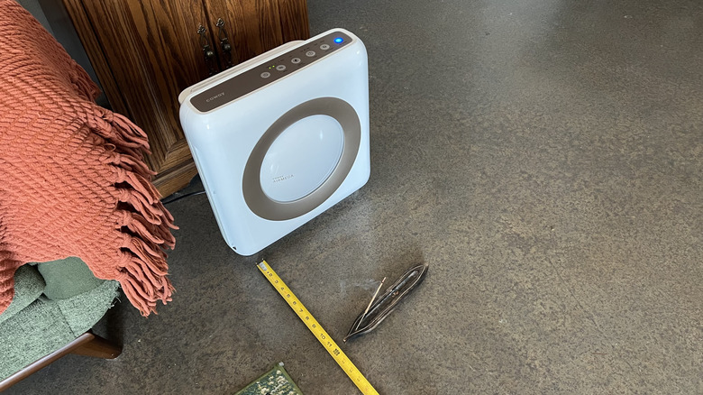 Coway Airmega Mighty AP-1512HH hava temizleyici, yanan tütsü ve ölçüm bandının yanında.