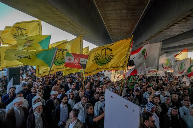 Göstericiler, 28 Eylül 2026 Pazartesi günü, Necef, Irak'taki Necef Uluslararası Havaalanı dışında Irak ile İran arasındaki uçuşların askıya alınmasına karşı düzenlenen protesto sırasında İran'a bağlı Iraklı milis grubu Harakat Hizbullah el-Nujaba'nın bayraklarını dalgalandırıyor. (AP Fotoğrafı/Anmar Khalil)