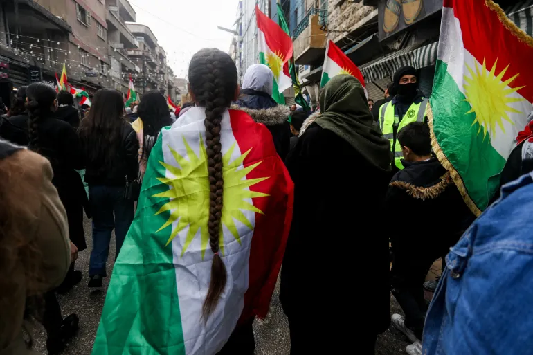 Kürt bayrağına sarılı bir kişi, 1 Şubat 2026'da Suriye'nin Kamışlı kentinde, Suriye anayasasındaki haklarını talep etmek ve Kürt birliğini desteklemek için Suriyeli Kürtlerin gösterisine katılıyor.