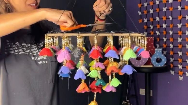 Renkli bir asılı çiçek dekoru parçasını kesen bir askı.
